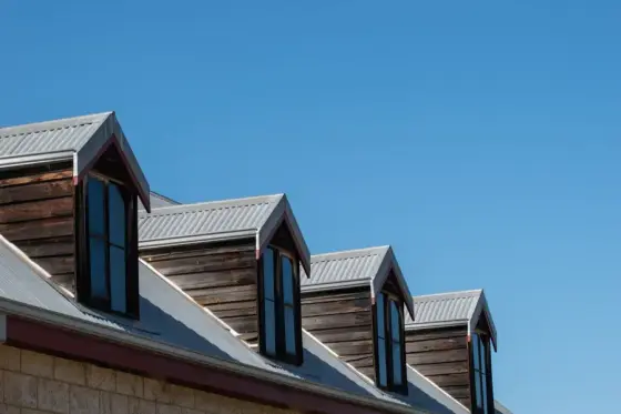 Dormers along a shingle roof against a blue sky